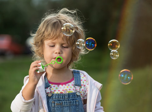 The little girl inflates soap bubbles