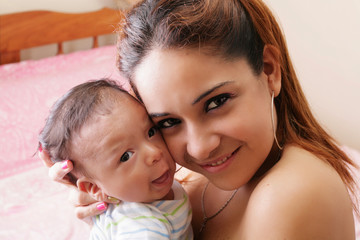 Portrait of a hispanic happy young mother holding a baby