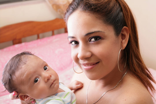 beautiful hispanic young mother is holding her newborn baby
