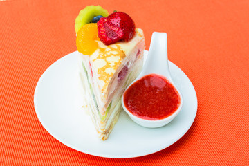 Crepes cake with orange, kiwi and strawberry sauce