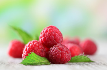 Ripe sweet raspberries on wooden table, on green background