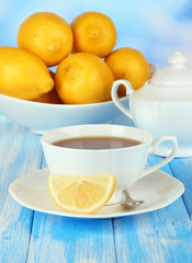 Cup of tea with lemon on table on blue background