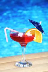 Tasty cocktail on swimming pool background