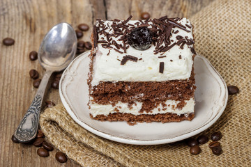 Chocolate and cherry cake. Coffee beans around, wooden back