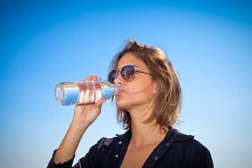 Beautiful woman drinking water at summer