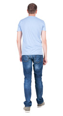 Back view of young man in t-shirt and jeans  looking. guy standi