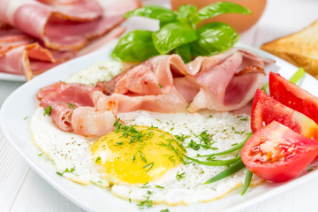 Fototapeta na wymiar Fried eggs with bacon and tomatoes