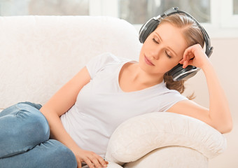 woman in headphones enjoys music while lying on the sofa at home