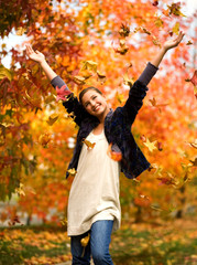 teen girl throwing leaves in autumn