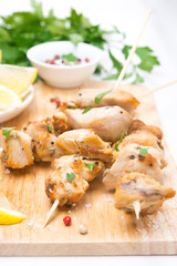 skewers of chicken with lemon and parsley on a wooden board