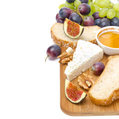 snacks - cheese, bread, figs, grapes, honey and nuts on a board