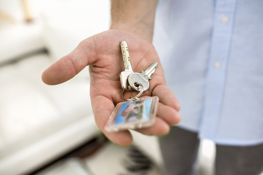 A man holds in his hand the keys of his house, indoor.