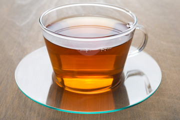 transparent glass cup of black tea on wooden background, closeup