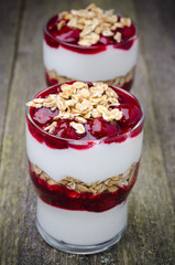 glasses with layered dessert with yogurt, cherries and granola