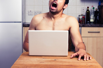 Young naked man watching pornography in his kitchen