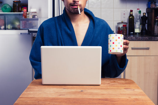 Man in robe working from home and smoking
