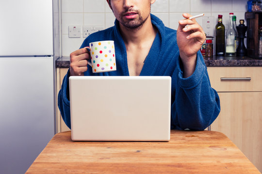 Man in robe working from home and smoking