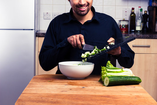 Happy man mixing a salad in kitchen