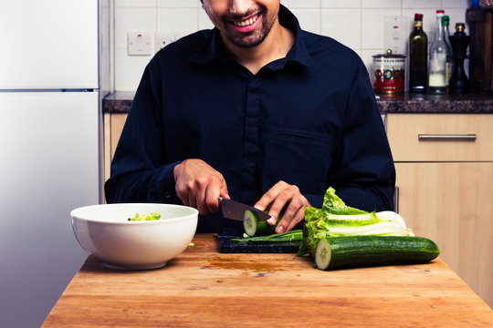 Happy young man making a salad