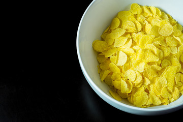 cornflakes in bowl on black table