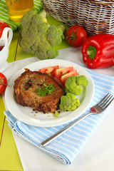Piece of fried meat on plate on wooden table close-up