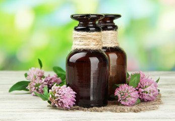 Obraz na płótnie Canvas Medicine bottles with clover flowers on wooden table, outdoors