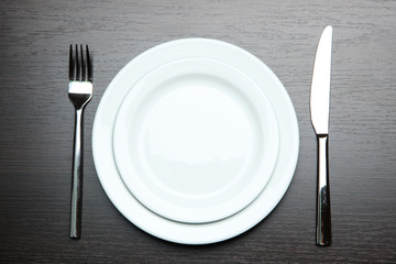 Knife, color plate and fork, on wooden background
