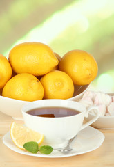 Cup of tea with lemon on table on light background