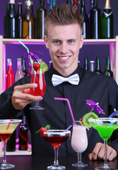 Portrait of handsome barman with different cocktails cocktail,
