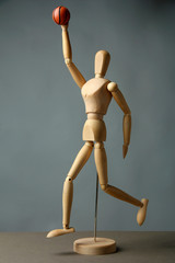 Wooden mannequin with basketball ball on grey background