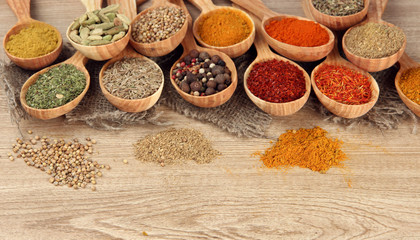 Assortment of spices in wooden spoons on wooden background