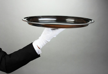 Empty tray in hand waiter on grey background