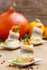 Pickled herring rolls with vegetables in autumn setting