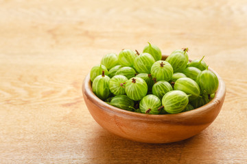 Close-Up Of Gooseberries In Vintage Wooden Bowl On Wooden Table