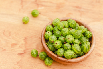 Close-Up Of Gooseberries In Vintage Wooden Bowl On Wooden Table