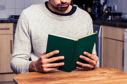 Young man reading in  his kitchen