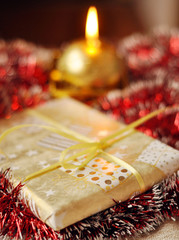 Christmas present and a lit candle on the red background