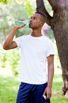 junger sportlicher mann trinkt wasser nach dem joggen