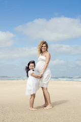 Fototapeta na wymiar Pregnant woman and her daughter on the beach