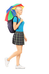 Full length portrait of a female student walking with umbrella