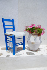 Traditional greek blue chair together with flowerpot