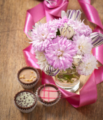 Beautiful aster flower bouquet and chocolates on wooden table