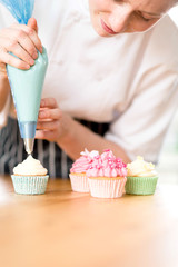 Fototapeta na wymiar Woman decorating homemade cupcakes with cream