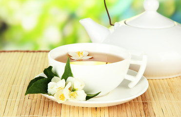 Cup of tea with jasmine, on bamboo mat, on bright background