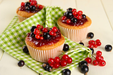 Tasty muffins with berries on white wooden table