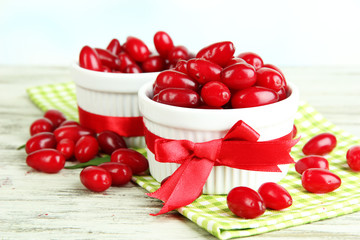 Fresh cornel berries in white cups on wooden table