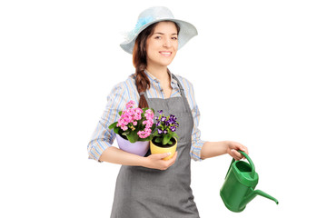 Female gardener holding flower pots and watering can