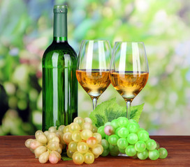 Fototapeta na wymiar Ripe grapes, bottle and glasses of wine, on bright background