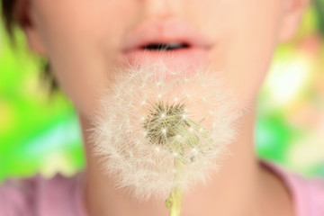 Girl blowing on dandelion close up