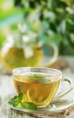 Cup of herbal tea with fresh mint flowers on wooden table